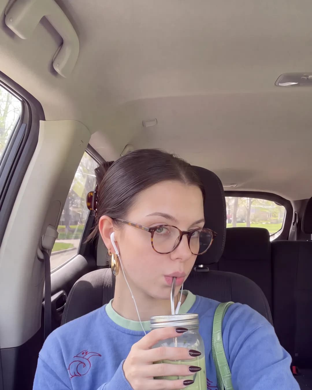Katherine in a car drinking matcha, blue sweatshirt