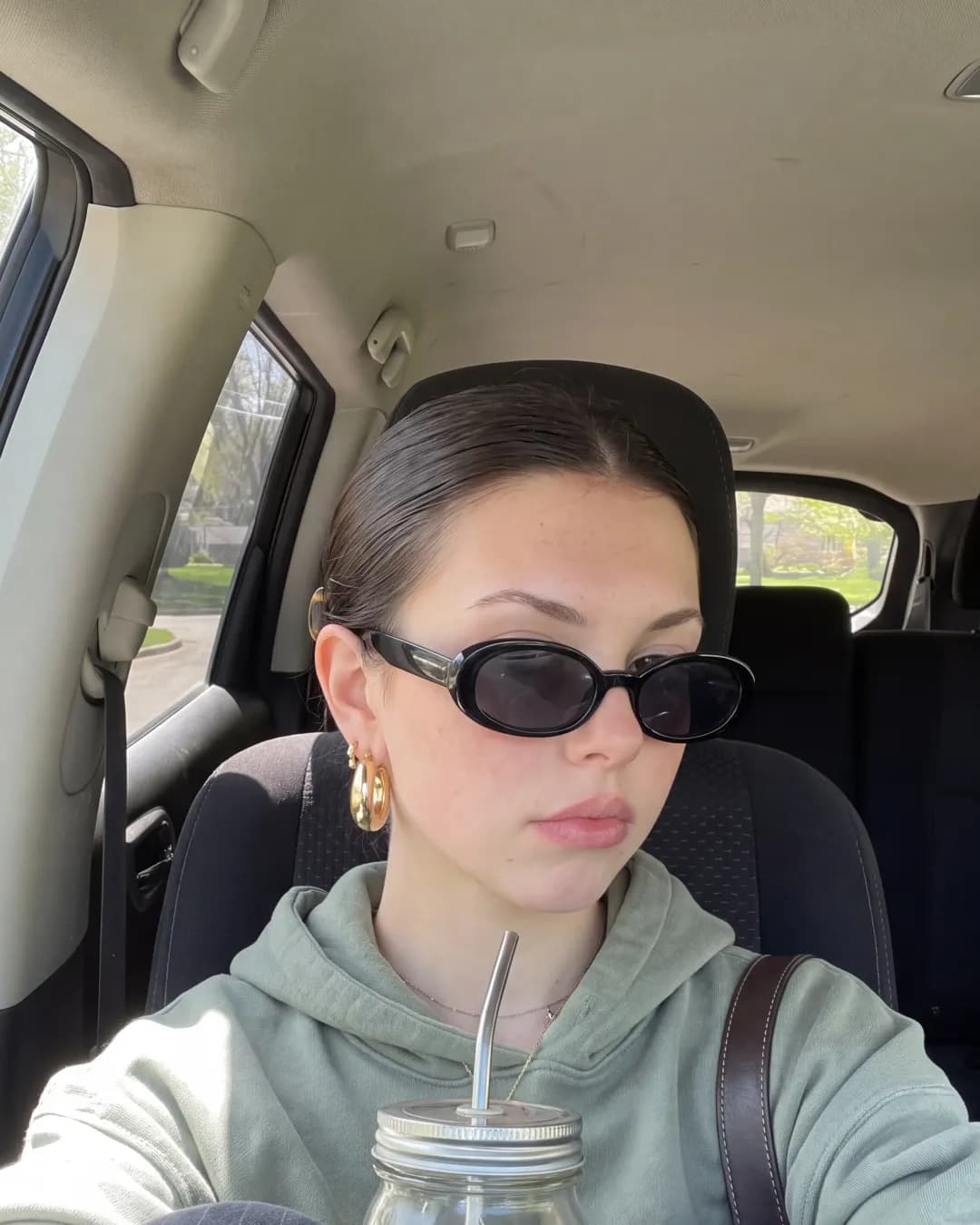 Katherine in the car, grey hoodie and sunglasses